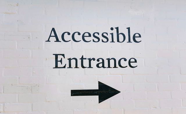 Words 'Accessible Entrance' painted onto brick wall with arrow pointing right.